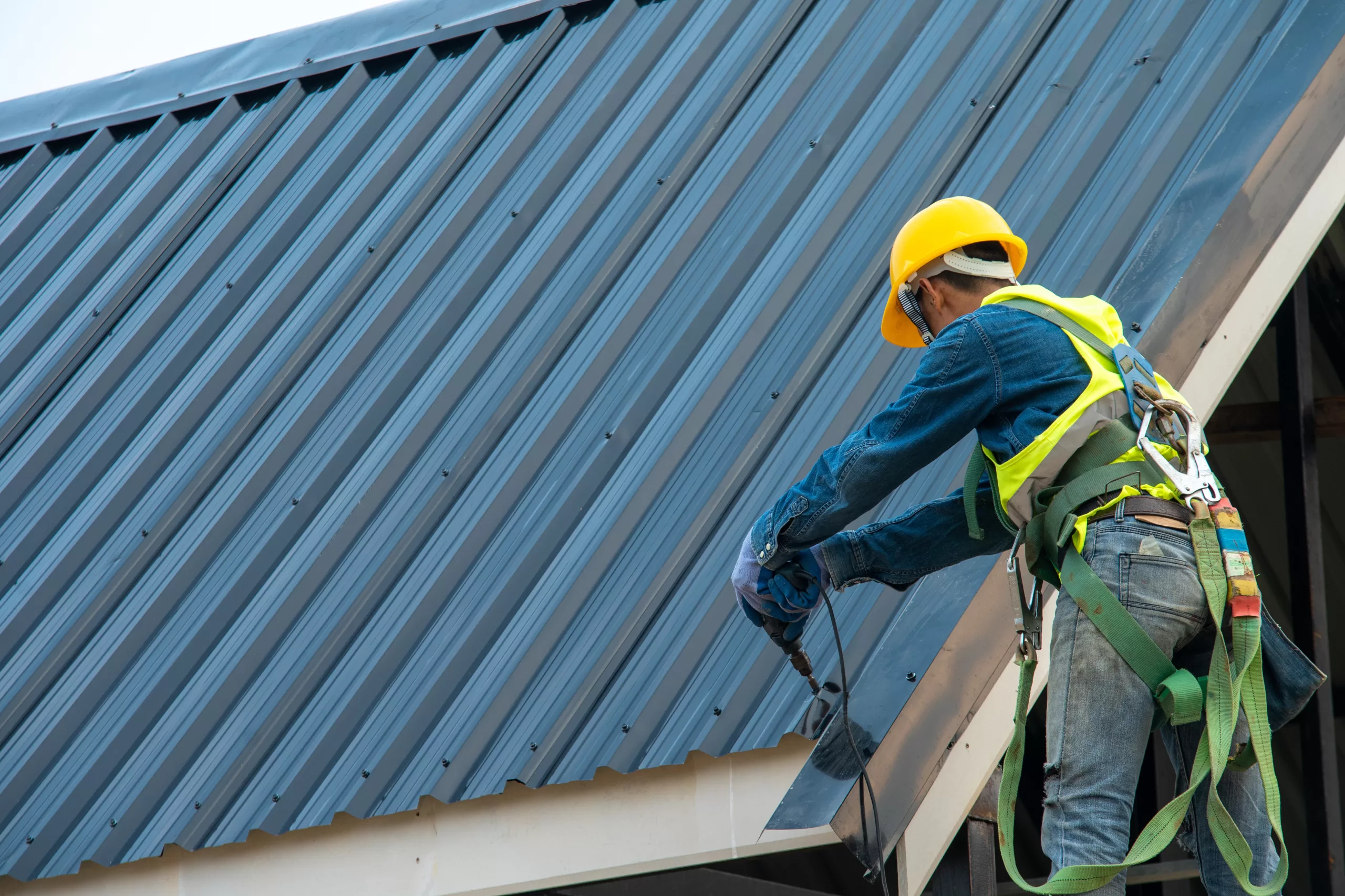 a roofer installing a metal roof on a building. roofing company marketing