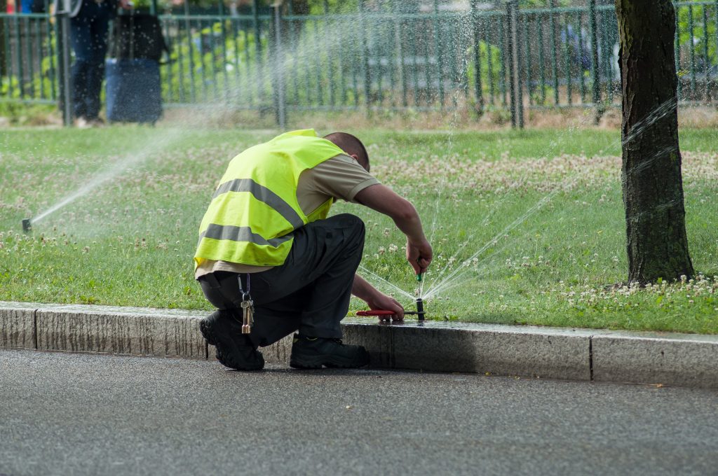 an irrigation expert adjusting automatic sprinklers on tramway line